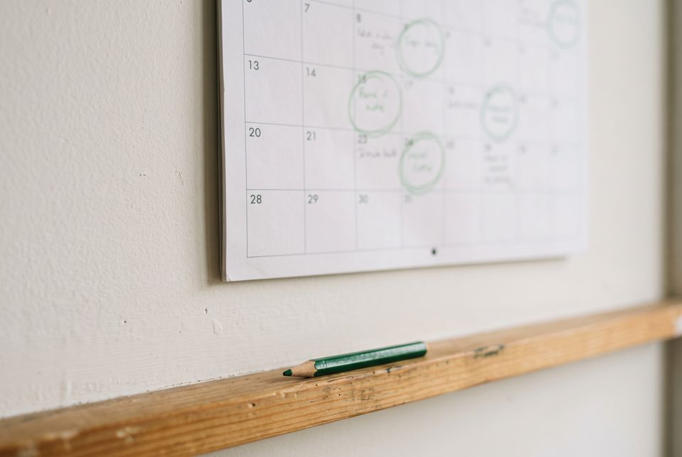A paper wall calendar with a few dates circled in green pencil
